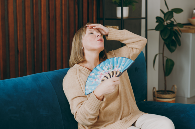 woman fanning herself indoors because she has a broken ac
